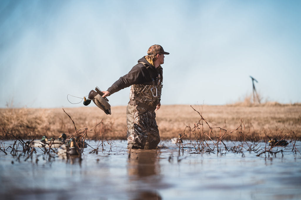a hunter with chest waders stands in the water